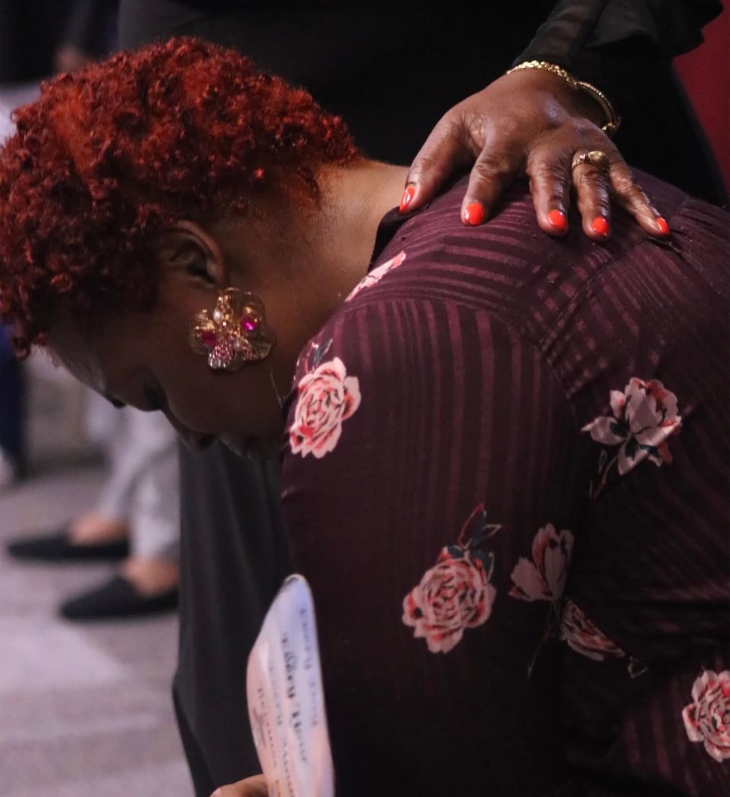 A hand resting on a member's shoulder in prayer at Advance Church