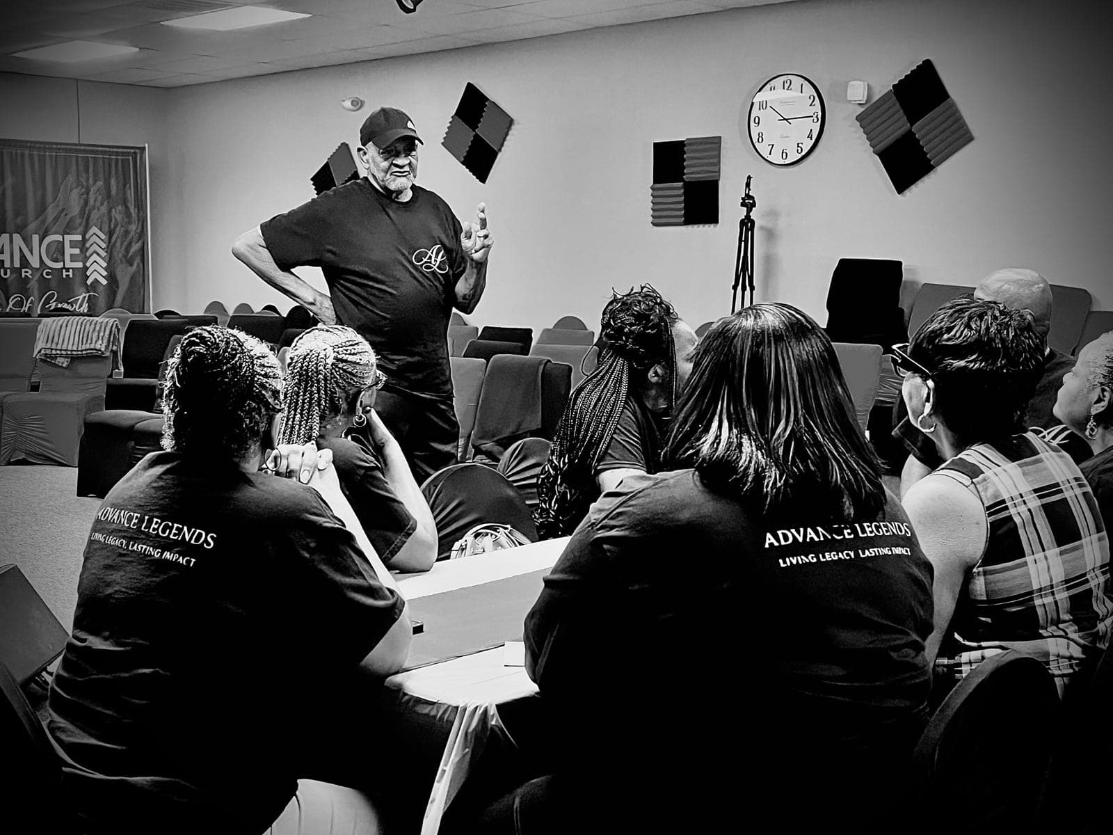 Advance Legends members in matching shirts seated around a table, listening to a leader teach