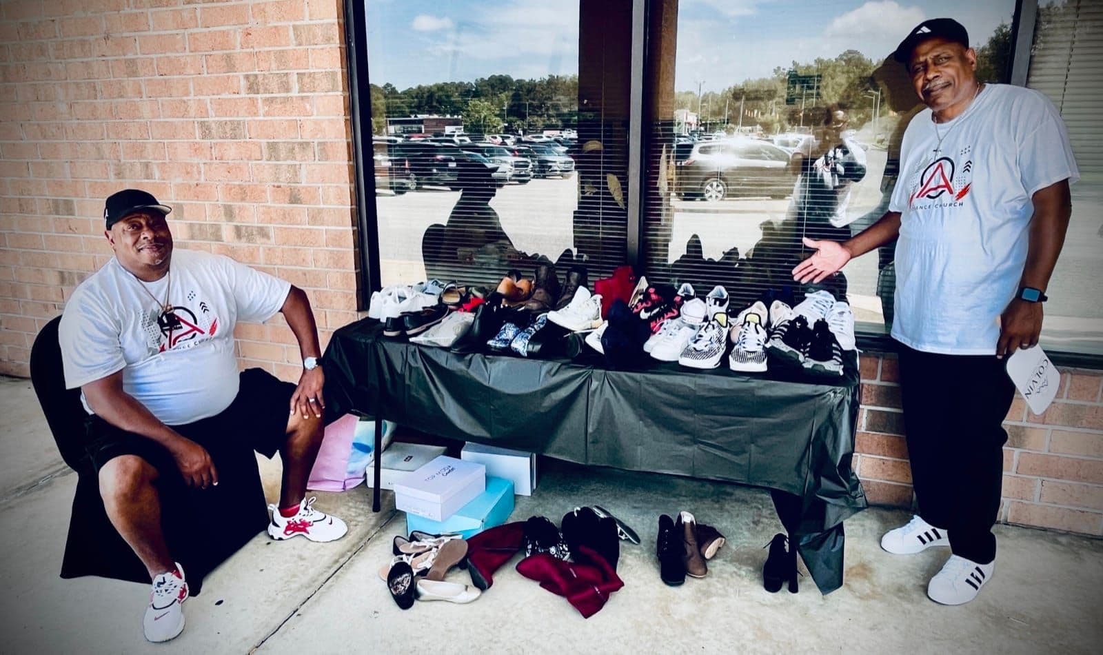 Two Advance Church volunteers at a table of donated shoes outside the church